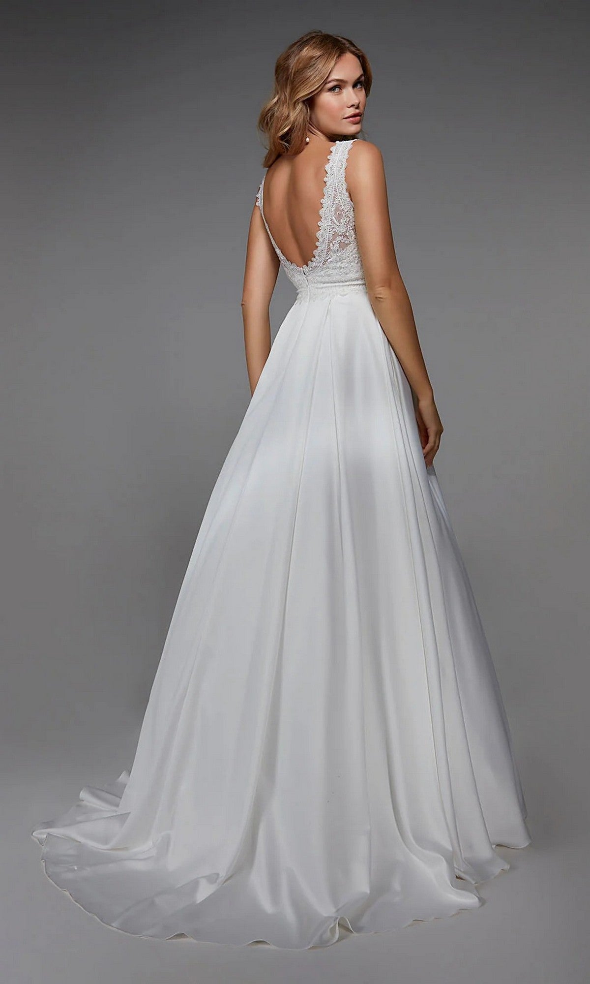 A woman models the Alyce 7035 long white dress, featuring a sleeveless lace bodice and deep V-back, as she stands facing away from the camera against a plain background.
